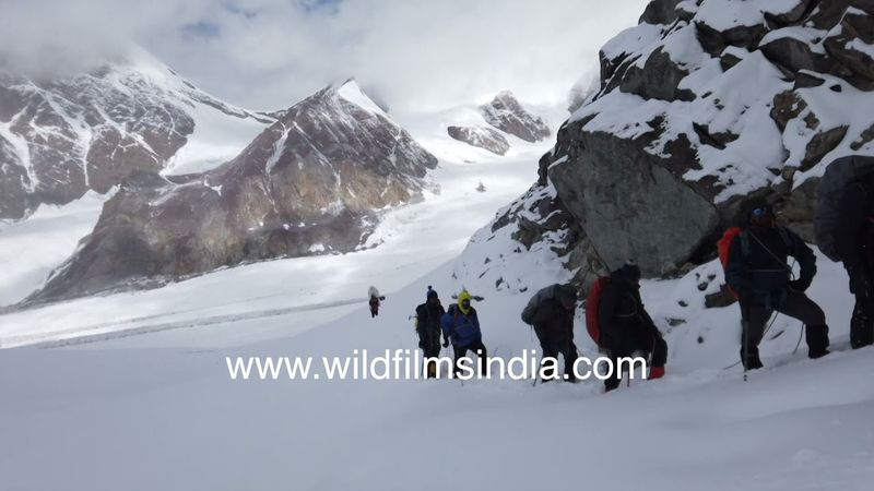 Plodding through knee deep snow on a rocky steep slope to top of Kalindi Khal Pass in Uttarakhand