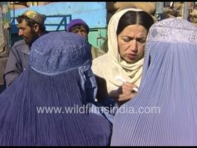 Afghani women buy groceries and grain in Afganistan, all attired in blue full body robes and burkhas