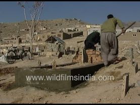 Graves and tombs being dug in Kabul Afghanistan, in 1990's. Women in blue walk walk vast landscape