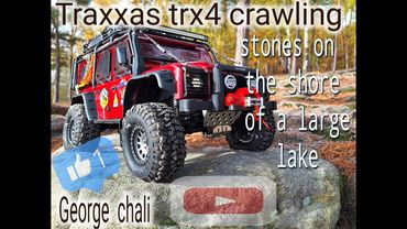RC Traxxas TRX4 crawlings stones on the of shore a large lake