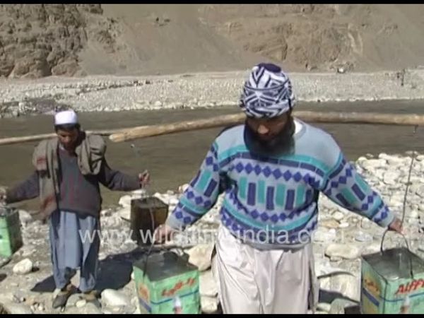 Taliban prisoners in chains carry water from rivebed in Afghanistan, as indentured labourers
