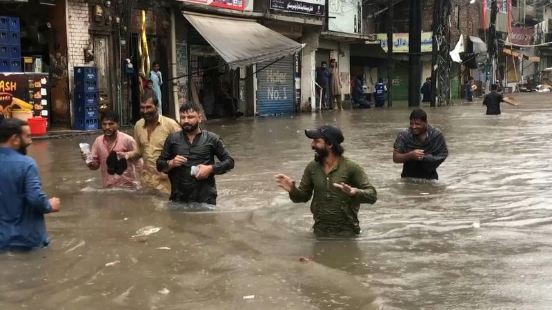 Pakistanis wade through waist-deep floodwater in Lahore after heavy rain | AFP