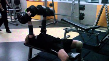 Девушка выполняет жим лежа с гантелями 30 кг